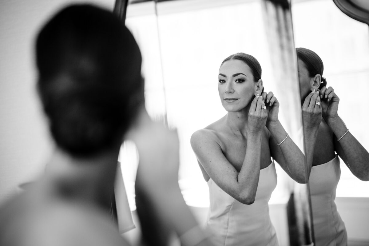 Bride putting on her earring while looking in the mirror at the Fairmont San Francisco. Photo by San Francisco Wedding Photographer Duy Ho