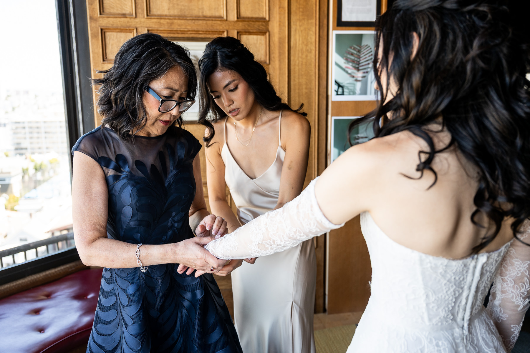 Mother fastening bracelet on bride's wrist by window during getting ready at Flood Mansion, San Francisco wedding