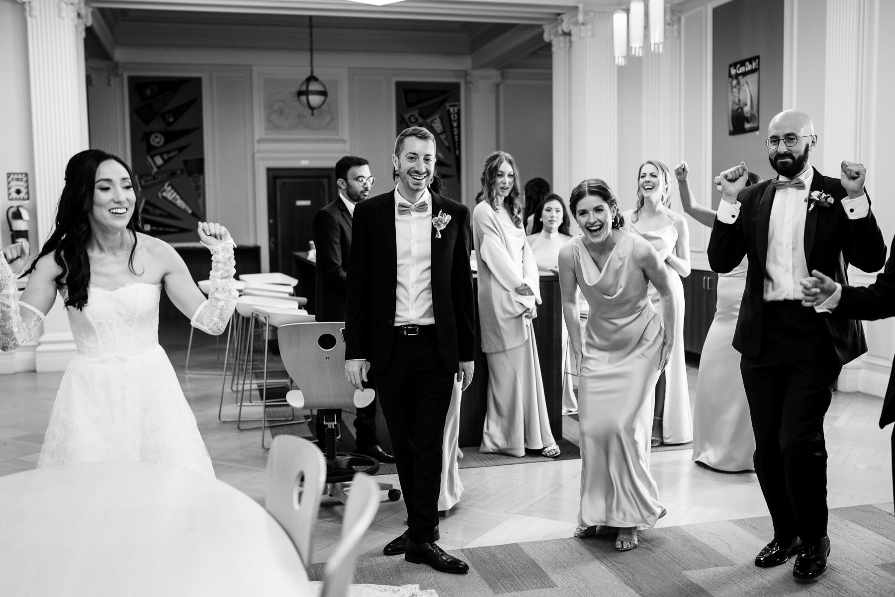 Black and white photo of groom waiting at altar as bride walks down Grand Hall aisle at Flood Mansion