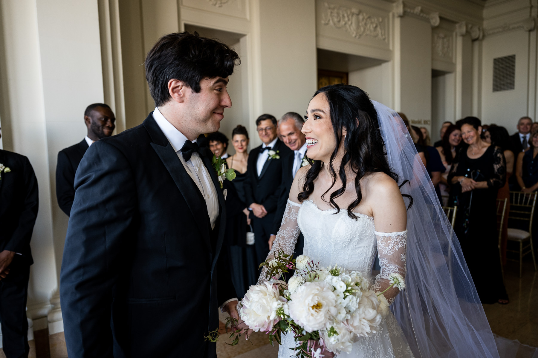Wide shot of wedding party at altar — bride and groom in Flood Mansion Grand Hall bay window with bridesmaids and groomsmen
