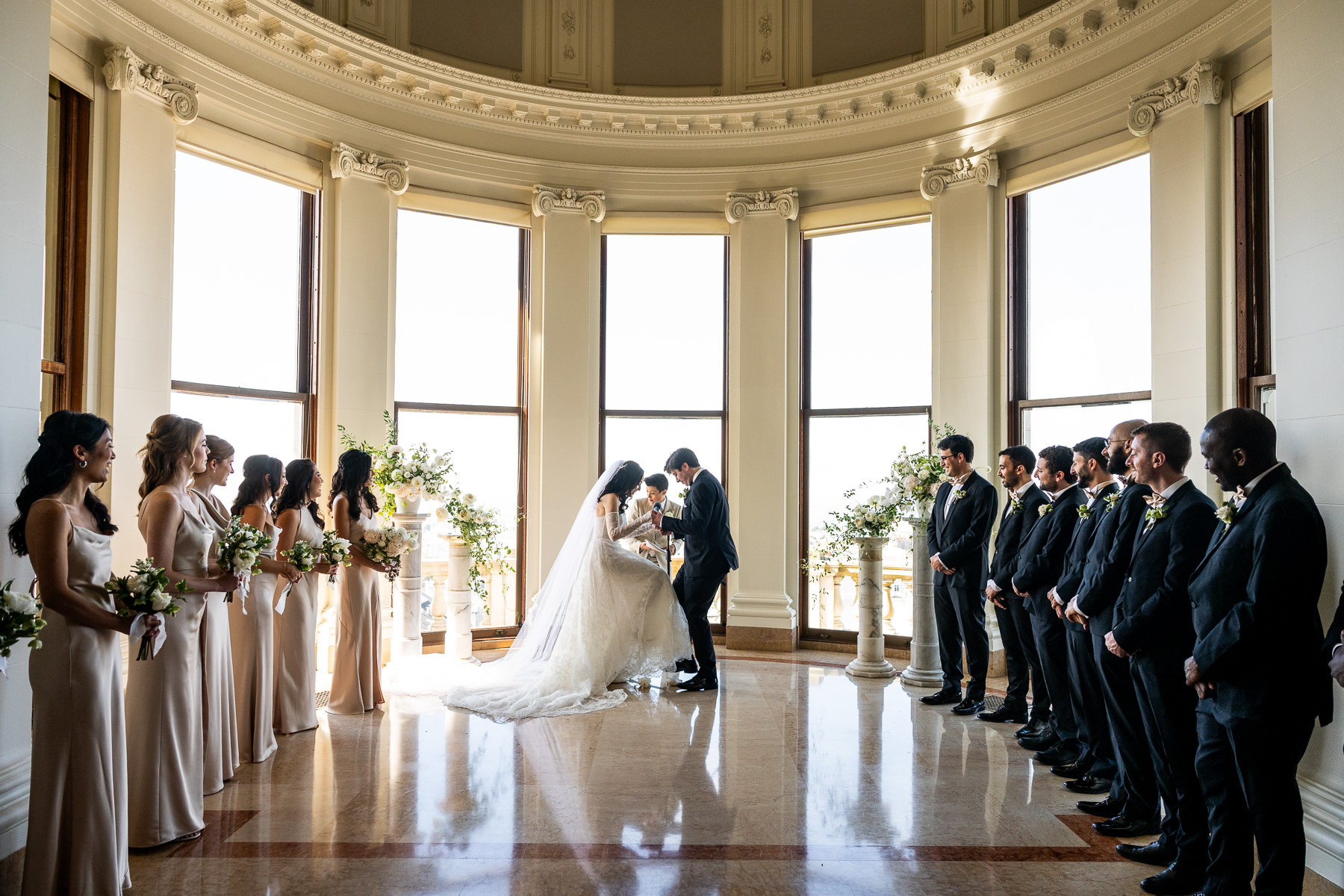 Newlyweds walking back up the aisle laughing as guests cheer, Flood Mansion Grand Hall ceremony recessional