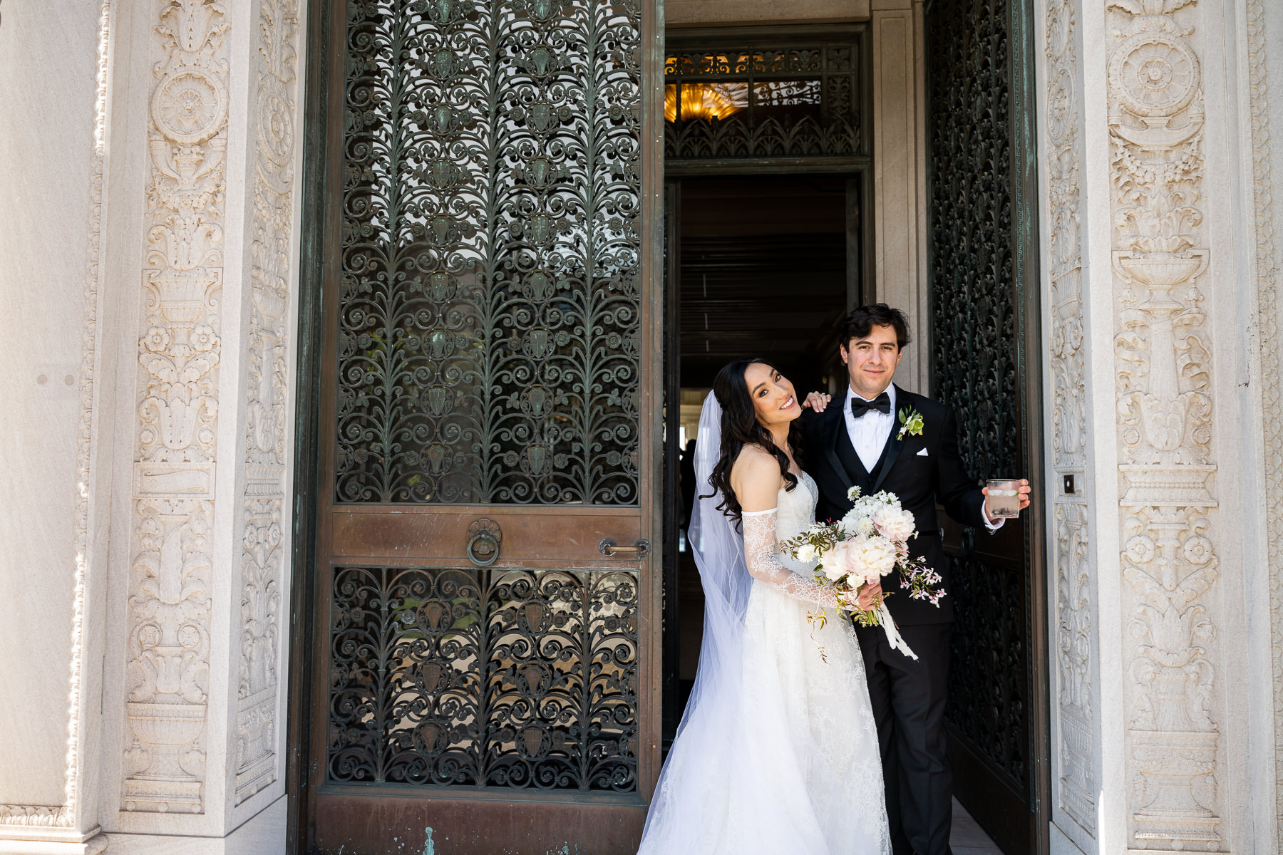 Black and white photo of bridesmaid arranging bride's cathedral veil at Flood Mansion entrance, Pacific Heights wedding