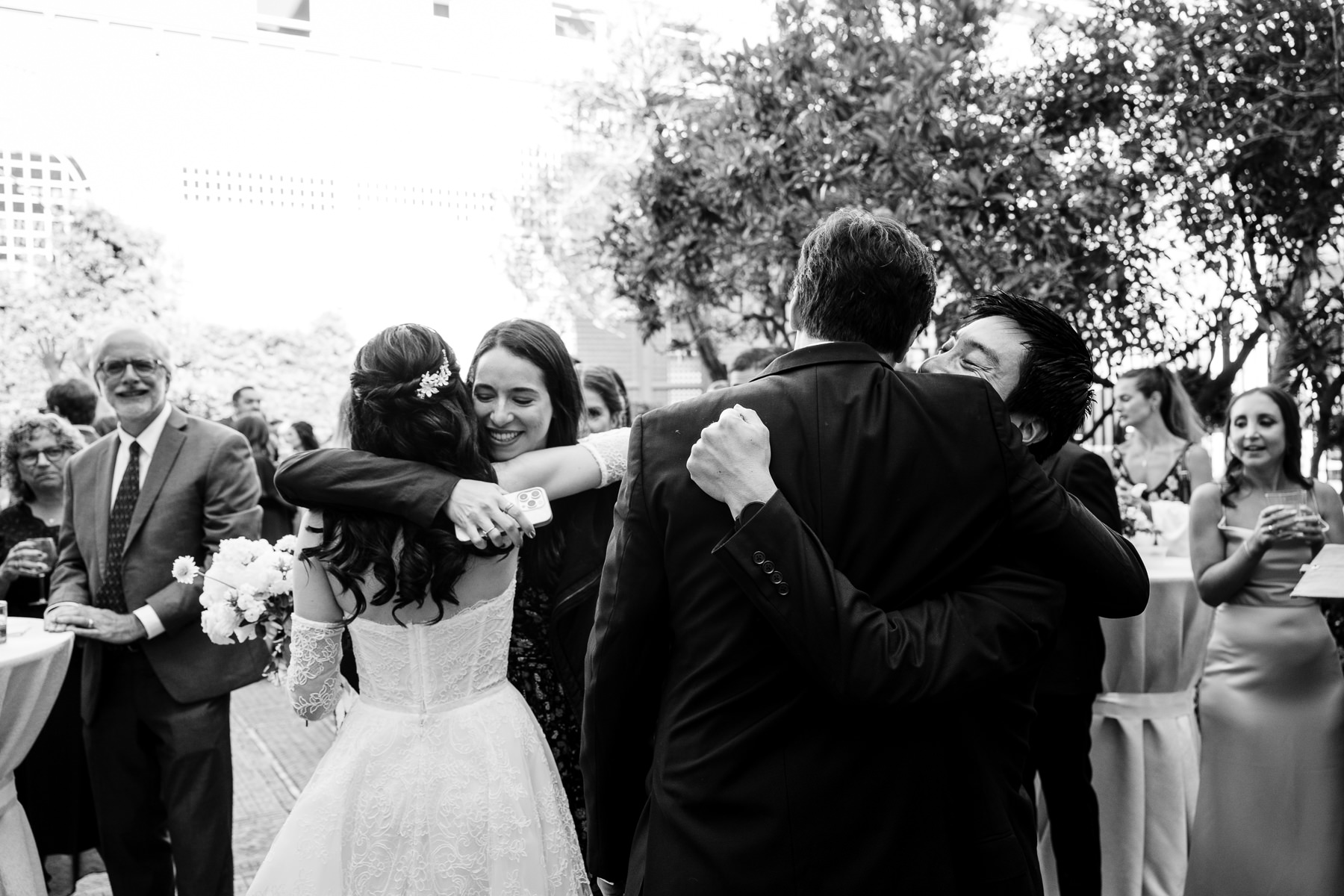 Bride embraced by guests after ceremony during cocktail hour in Flood Mansion courtyard, San Francisco wedding