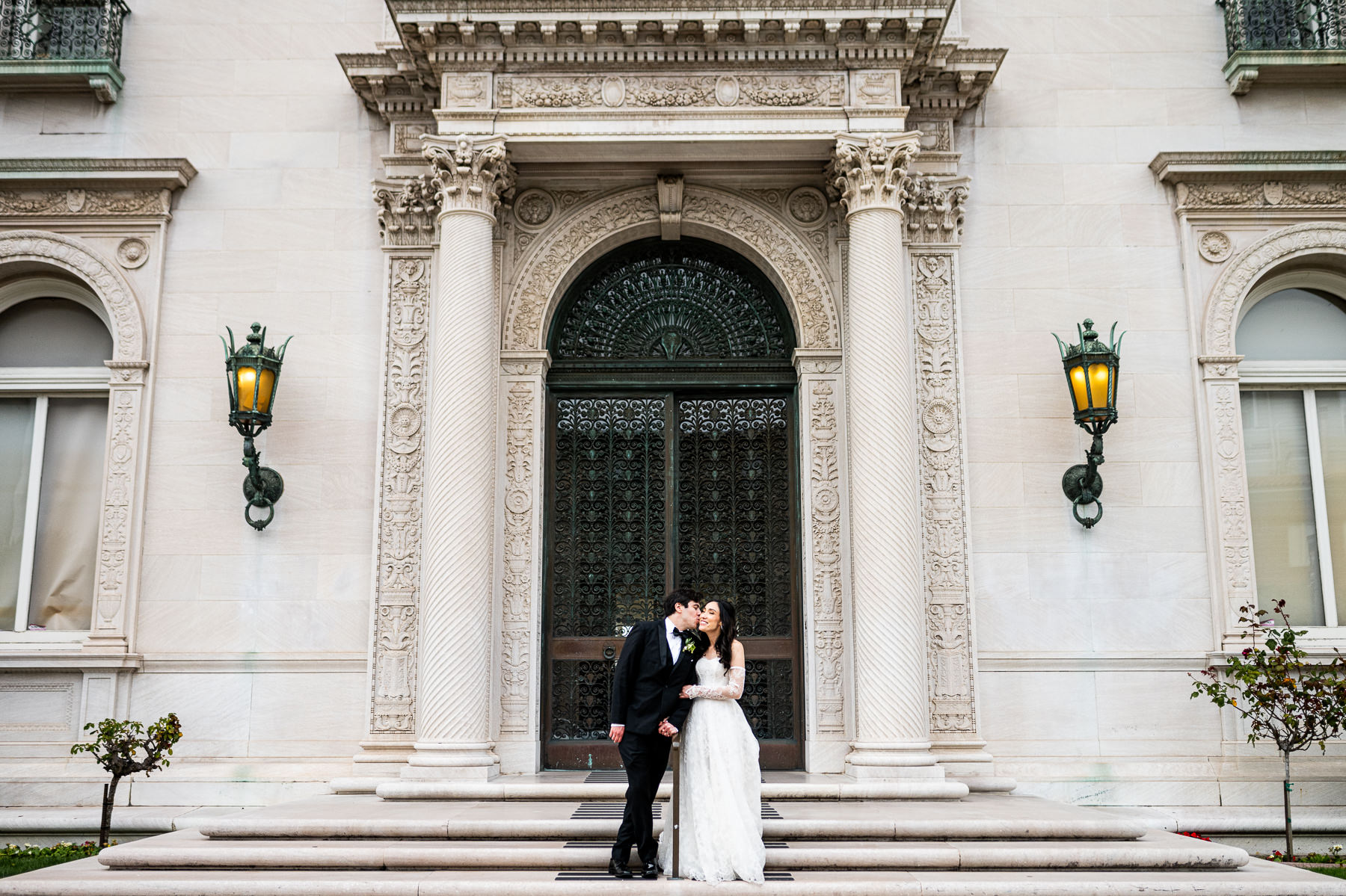 Couple portrait at Flood Mansion grand entrance steps with columns and iron lanterns, San Francisco mansion wedding