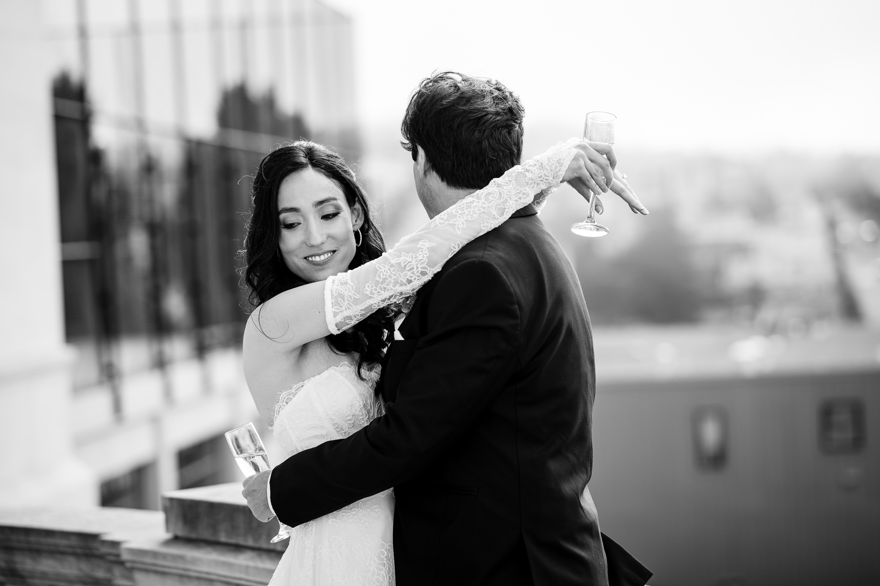 Black and white portrait of groom spinning bride on Flood Mansion rooftop terrace, San Francisco cityscape visible