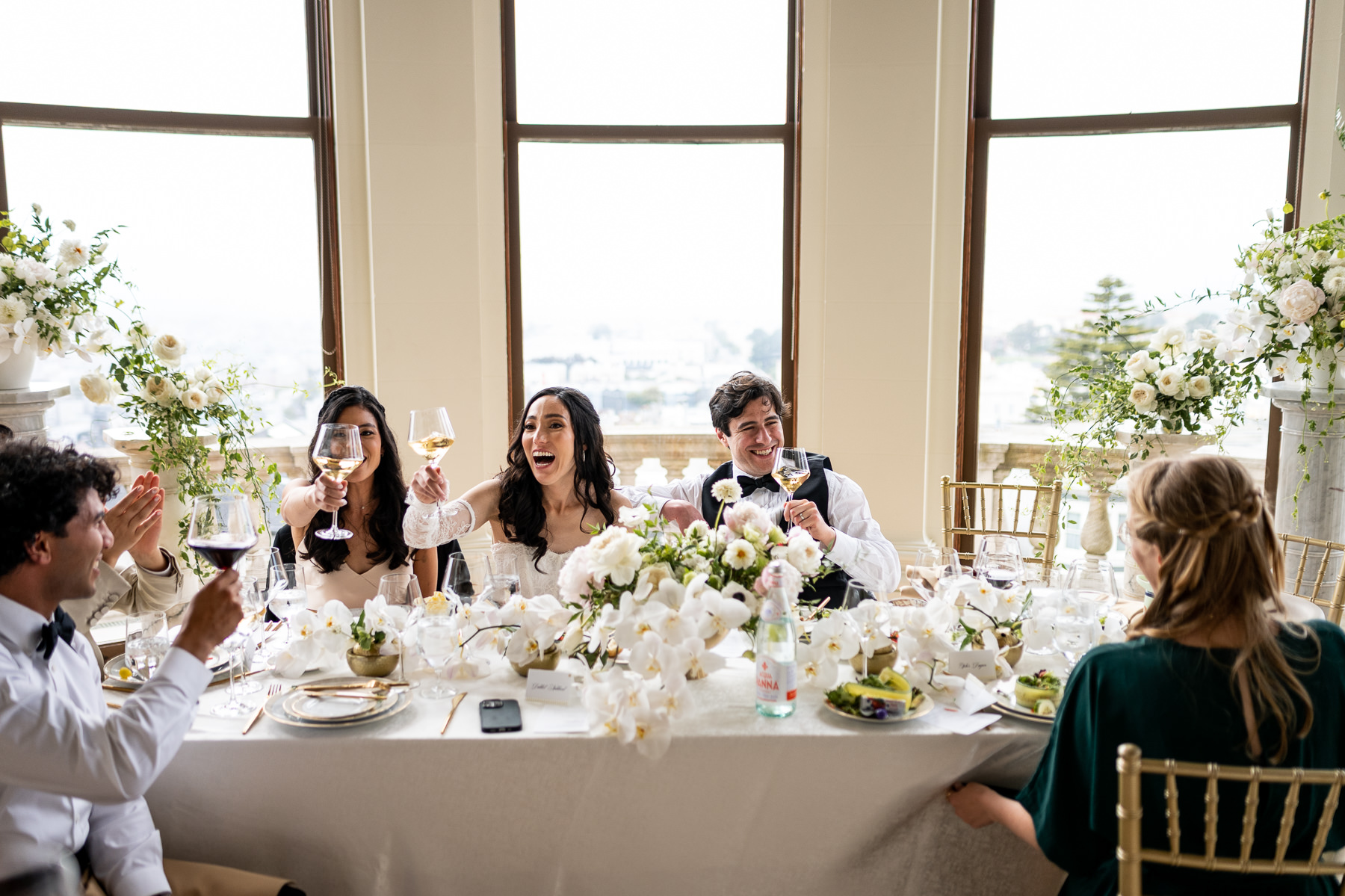 Guest giving toast at Flood Mansion wedding reception in Grand Hall, guests laughing and raising glasses, San Francisco