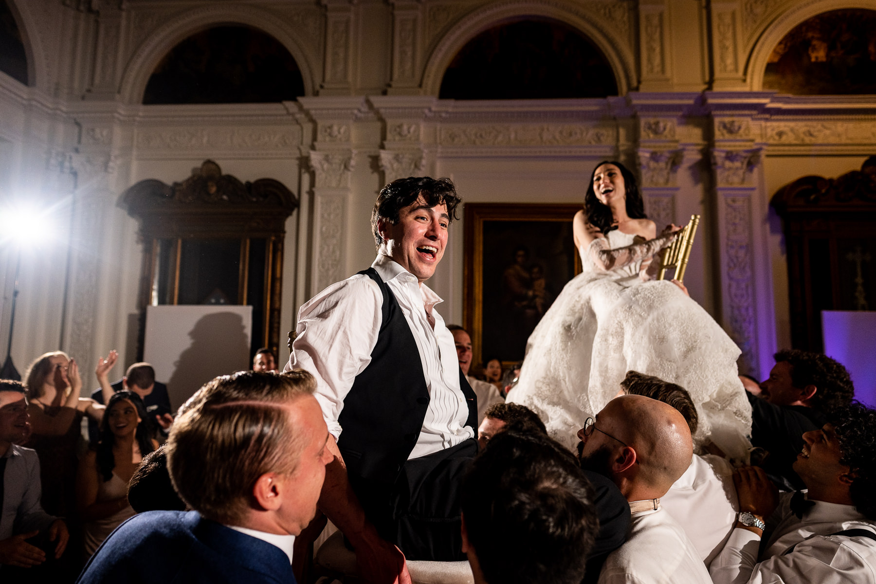 Wide shot of guests lifting bride during Hora at Flood Mansion Grand Hall reception, San Francisco mansion wedding